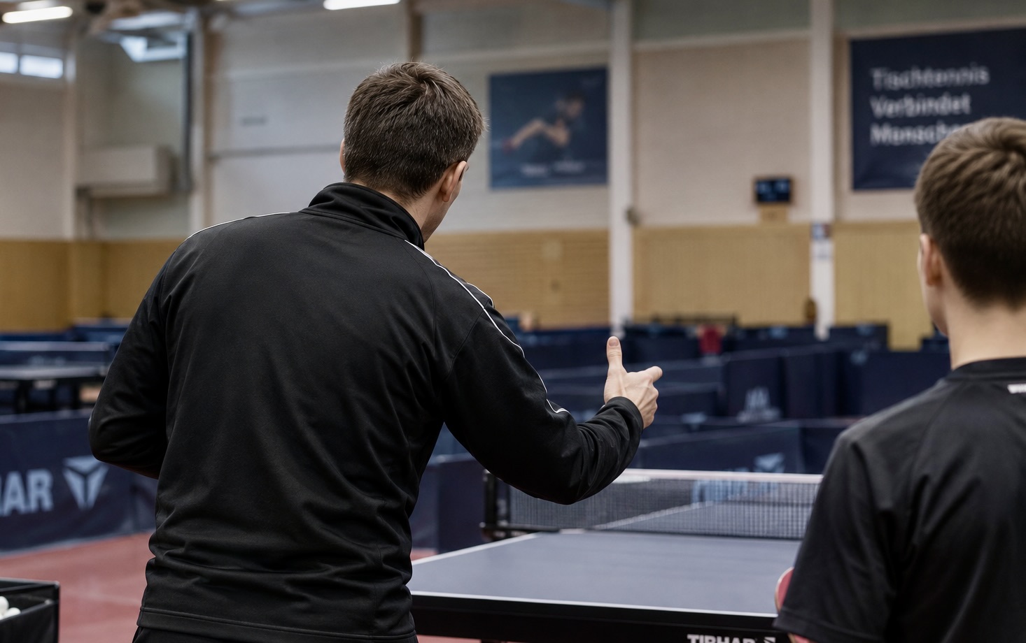 Tischtennistrainer erklärt einem Schüler etwas